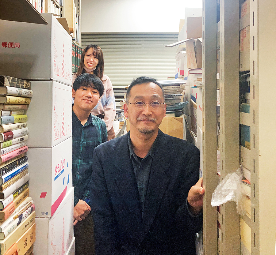 大量の本に囲まれた菊地暁先生（一番手前）の研究室にて